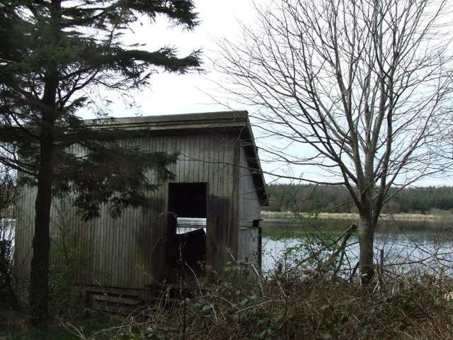 A wooden birdwatching hide on the north-eastern shore of the Cefni reservoir, overlooking open water.